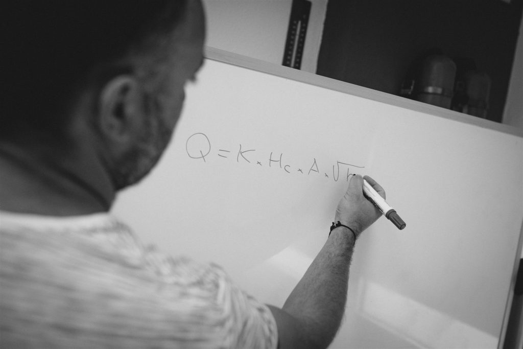 Imagen profesor escribiendo en una pizarra blanco y negro